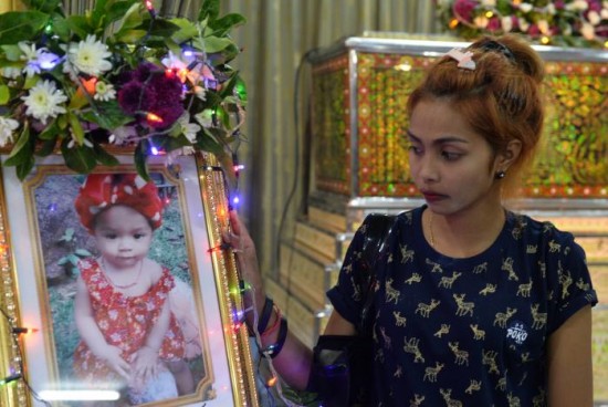 Jiranuch Trirat, mother of 11-month-old daughter who was killed by her father, stands next to a picture of her daughter at a temple in Phuket